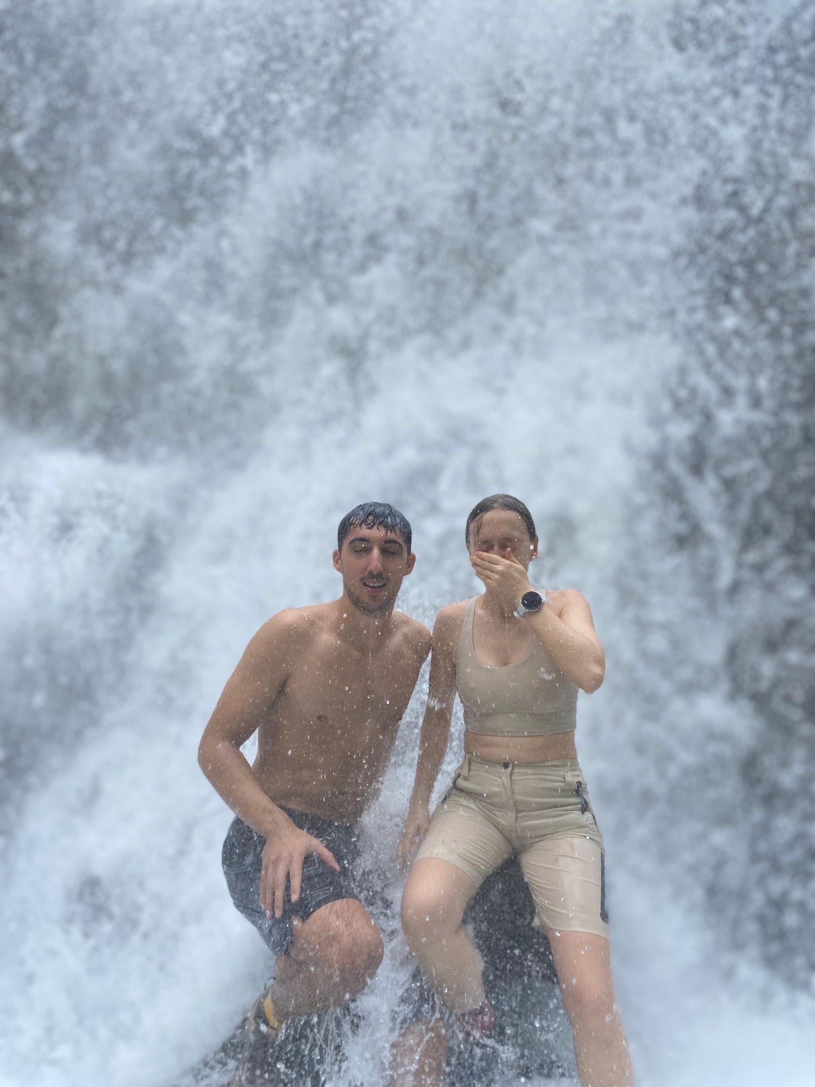 Travelers standing at the panoramic viewpoint overlooking the majestic Tumpak Sewu Waterfall in East Java, surrounded by lush tropical cliffs and cascading waterfalls.